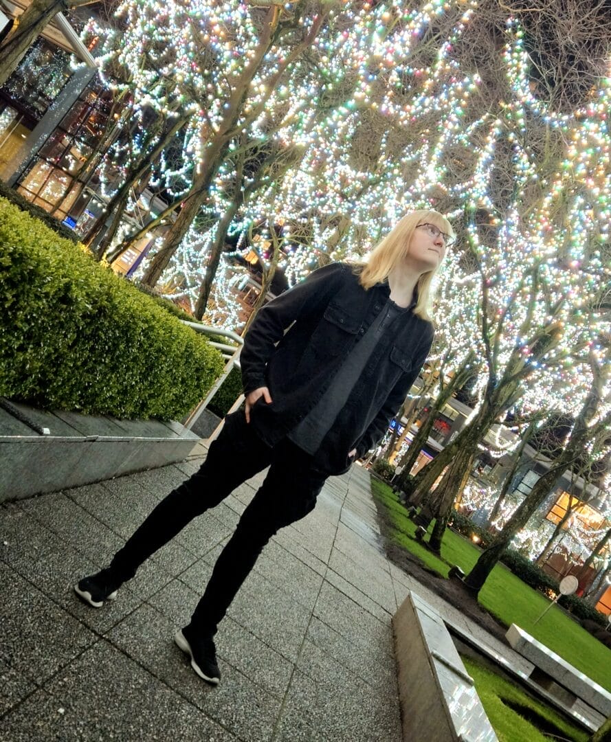 Audio Engineering & Production Grad, Sam McElroy posing for a photo under twinkling lights.  