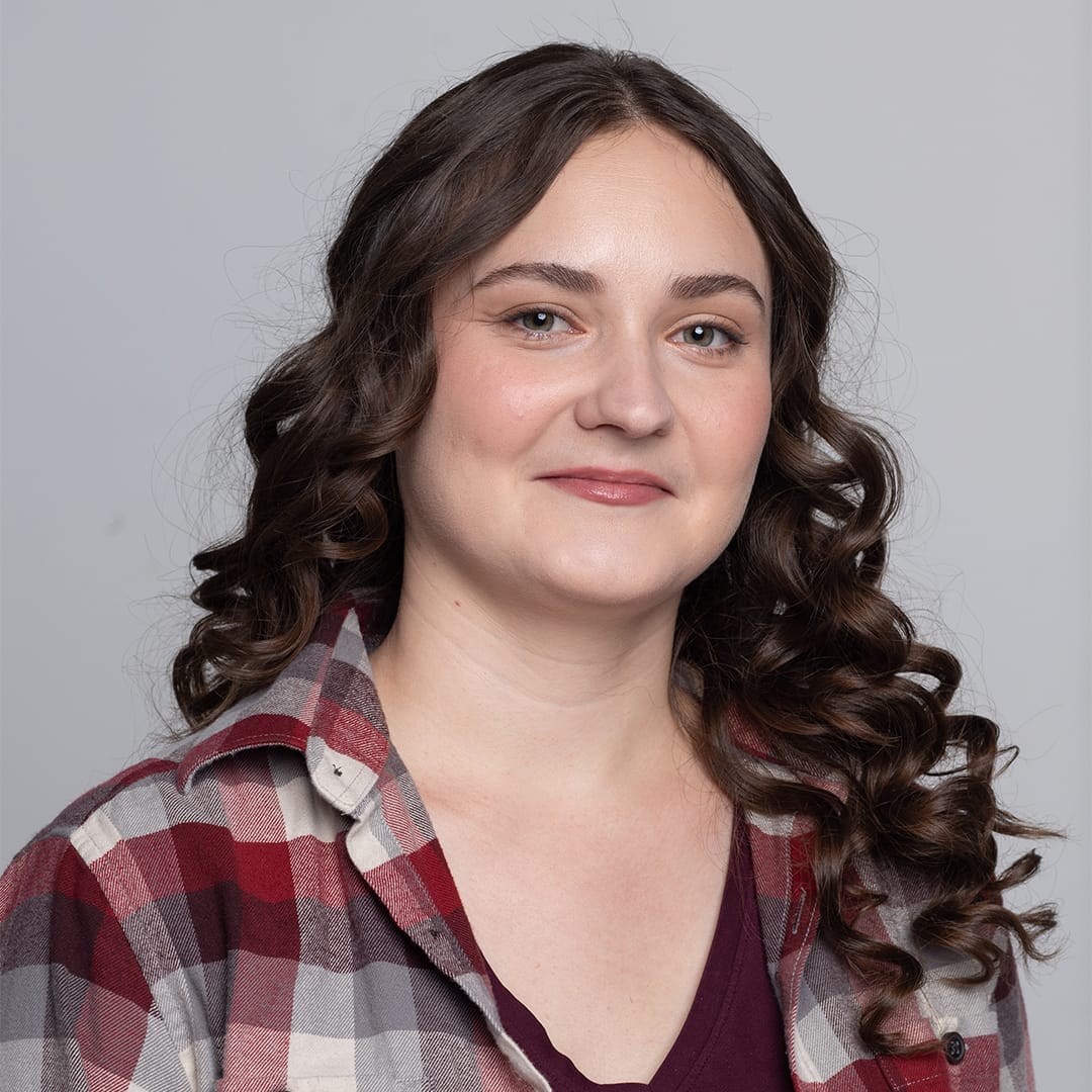 A woman in a plaid shirt is posing for a photo.