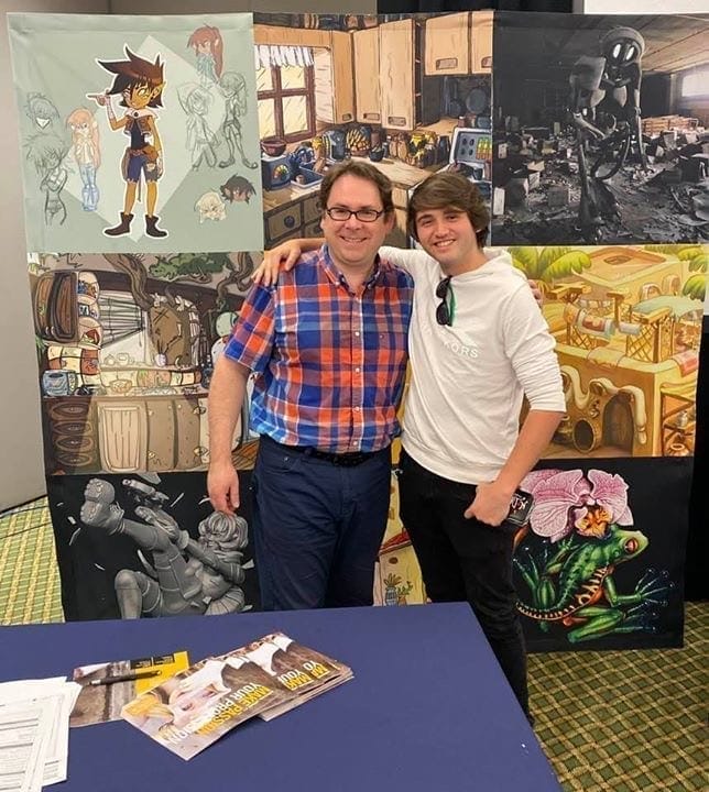 Two men posing in front of a display of cartoons.