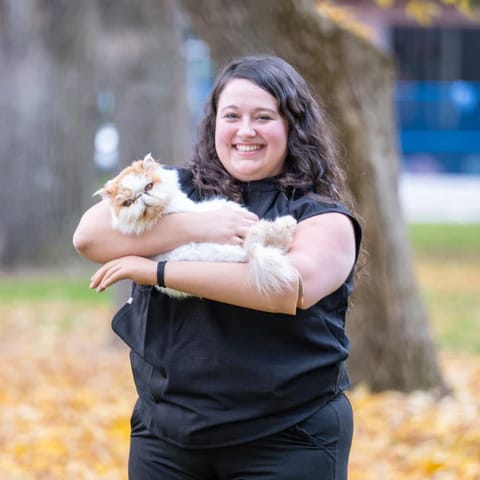 Veterinary Hospital Assistant Graduate, Alexandra Starker smiling while holding a cute cat. 