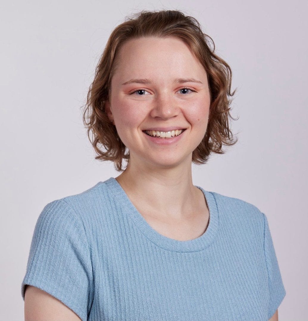 A smiling young woman in a blue shirt.