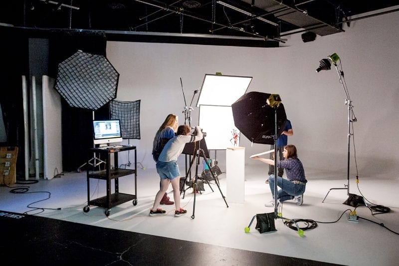 A group of people working in a studio with lighting equipment.