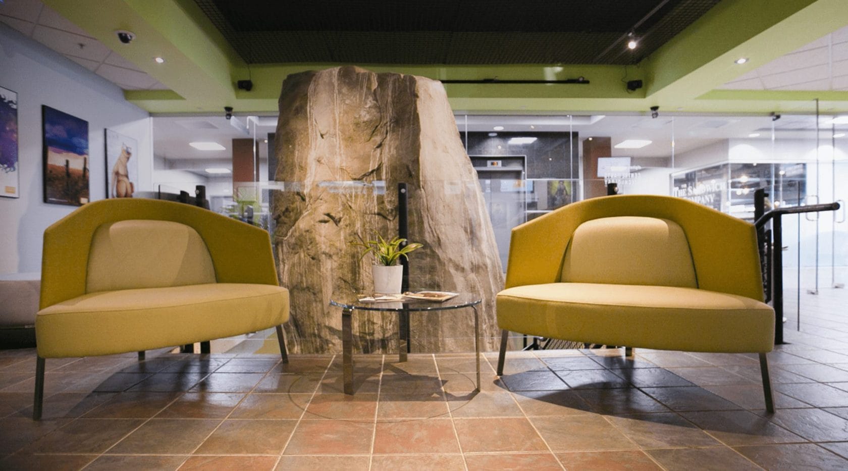 Two chairs in a lobby with a tree stump in the middle.