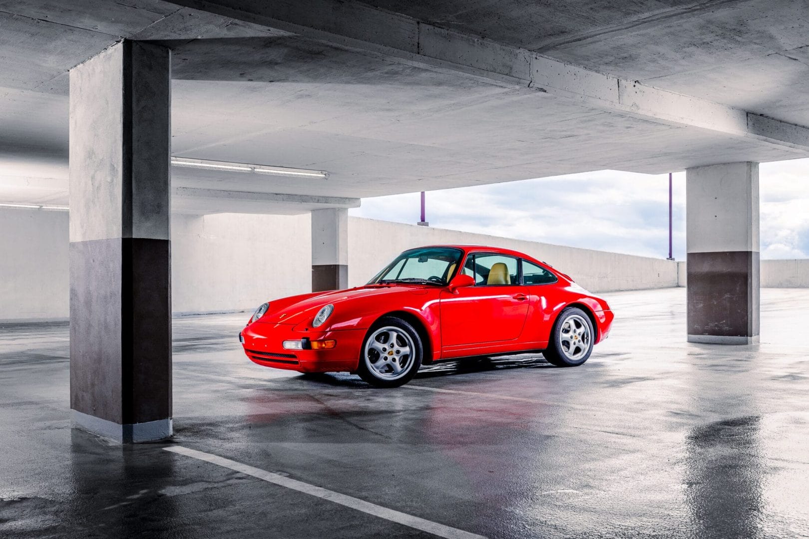 A red porsche 911 parked in a parking garage.