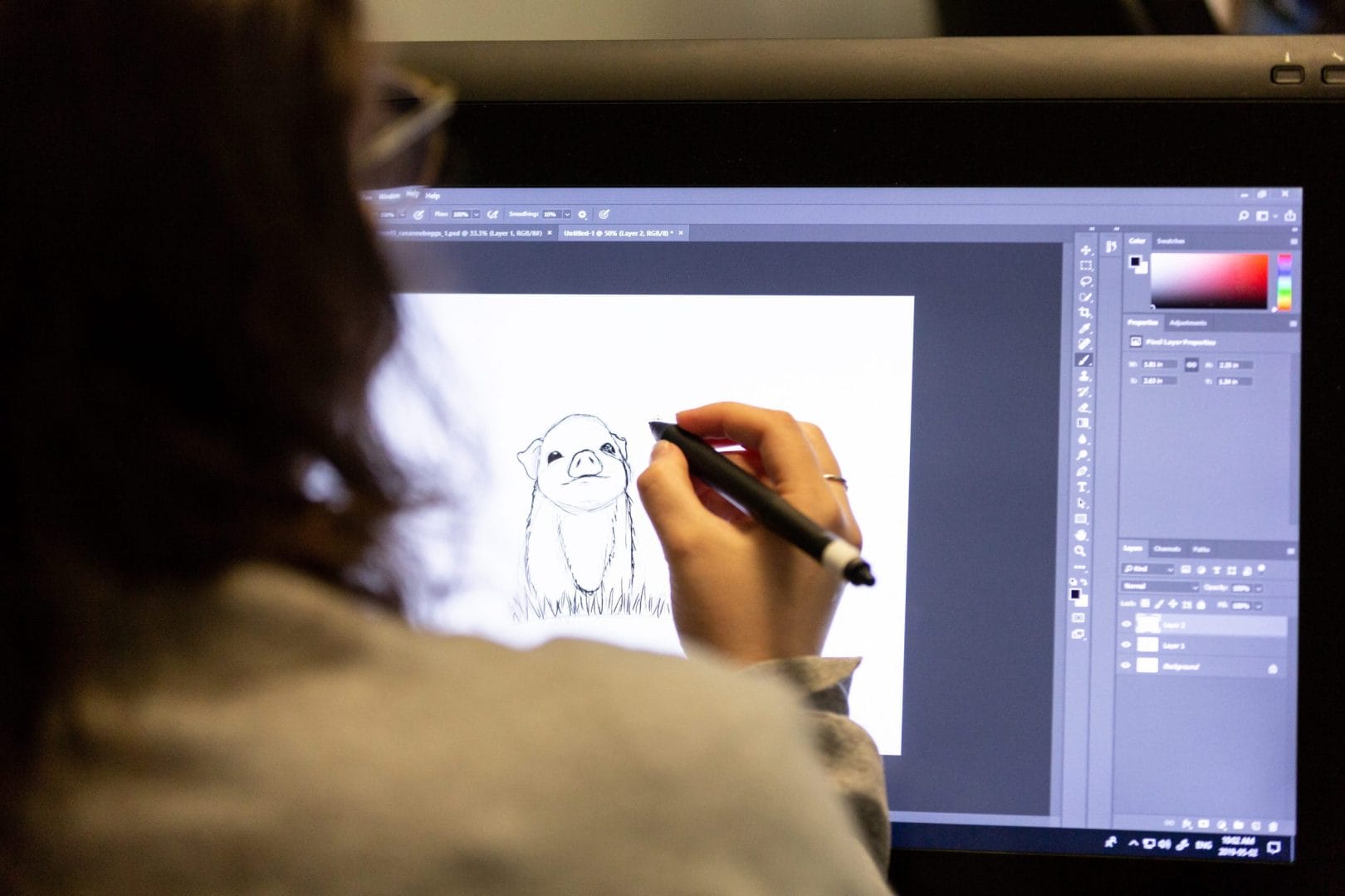 A CAT digital illustration student is drawing on a computer screen.