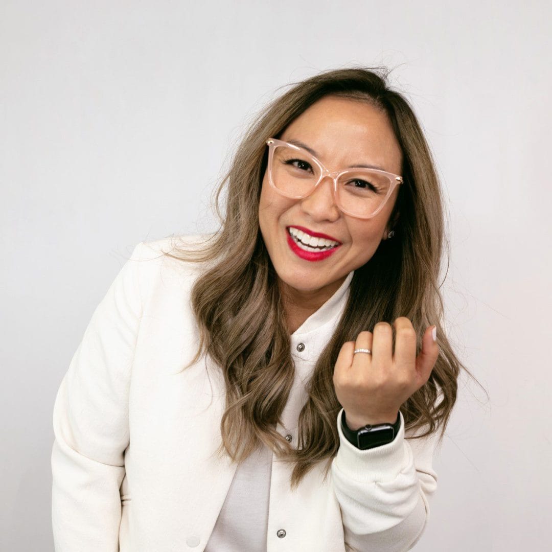 A woman wearing glasses and a white jacket.