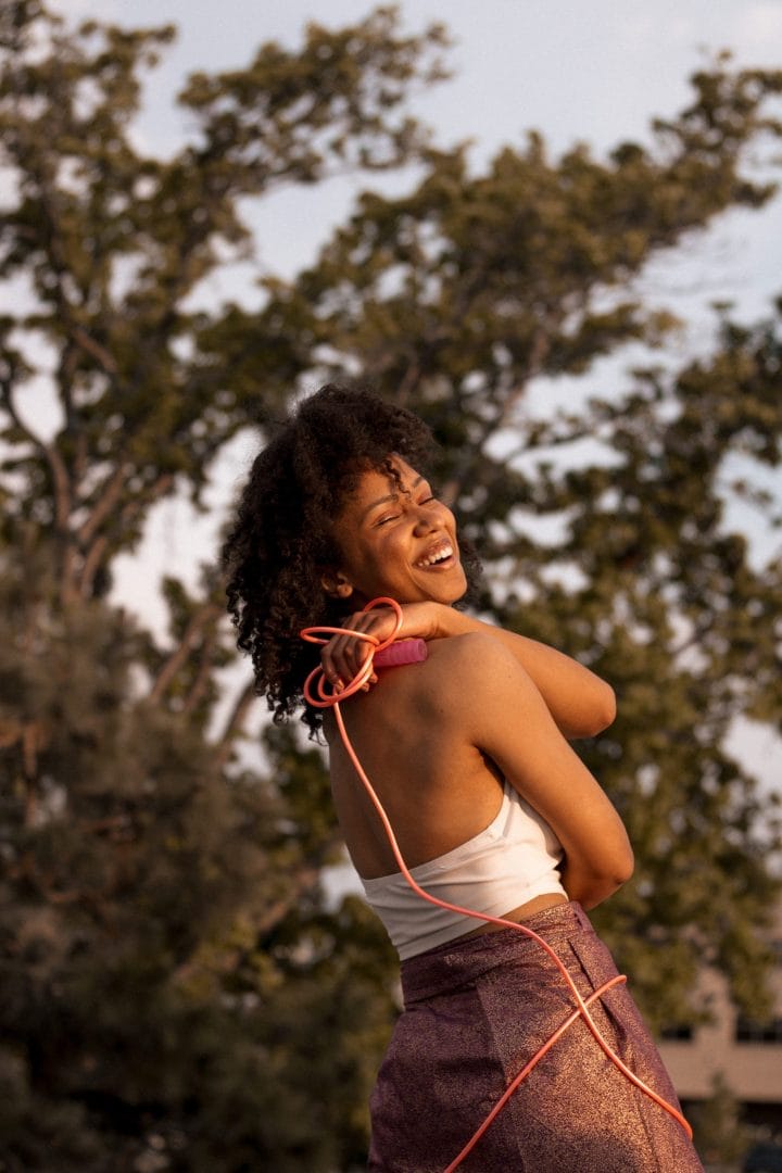 A woman wearing a skirt and listening to earphones.