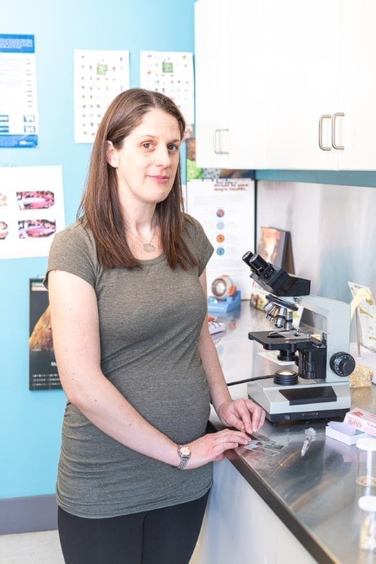 A woman standing in front of a microscope.