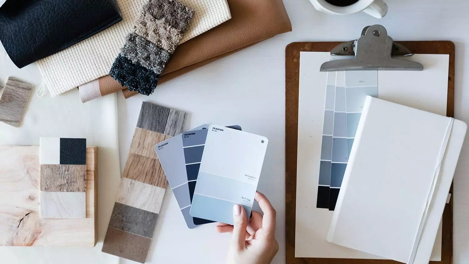 A person holding a paint palette and a cup of coffee.