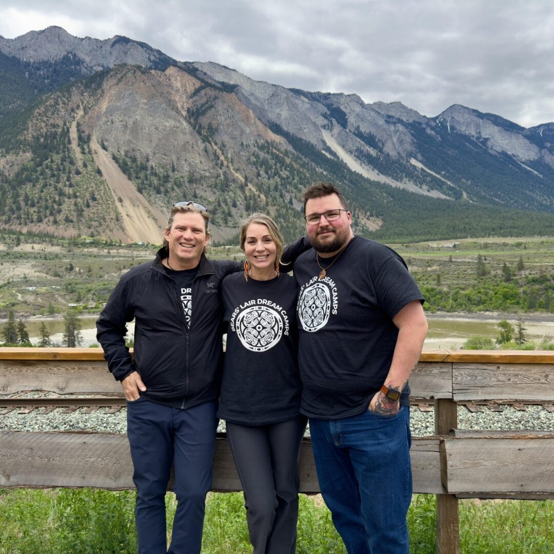 Professional Filmmaking grad, Jay Falkus, poses against a scenic background with his team members from Bears' Lair TV.