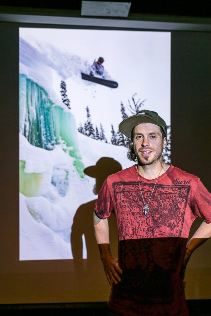 A man standing in front of a projection of a snowboarder.