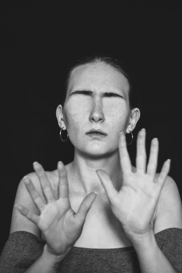 A black and white photo of a woman with her hands up.