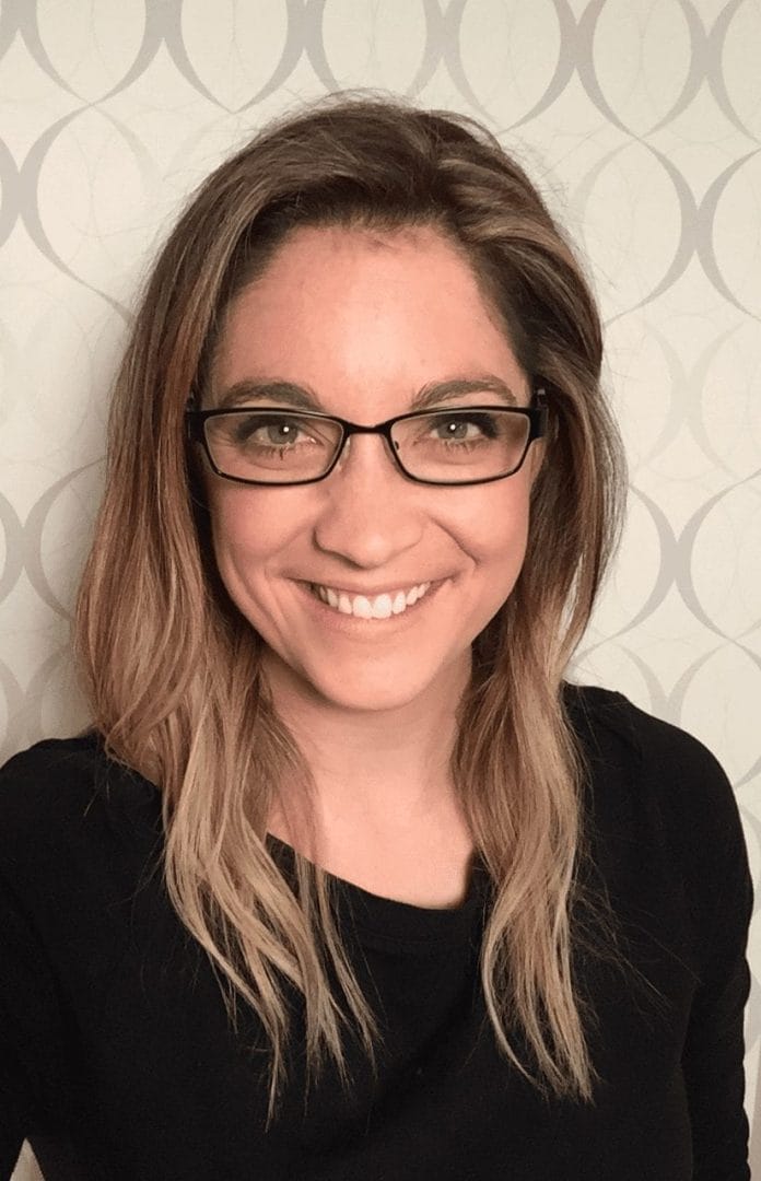 A woman in glasses smiling for the camera.