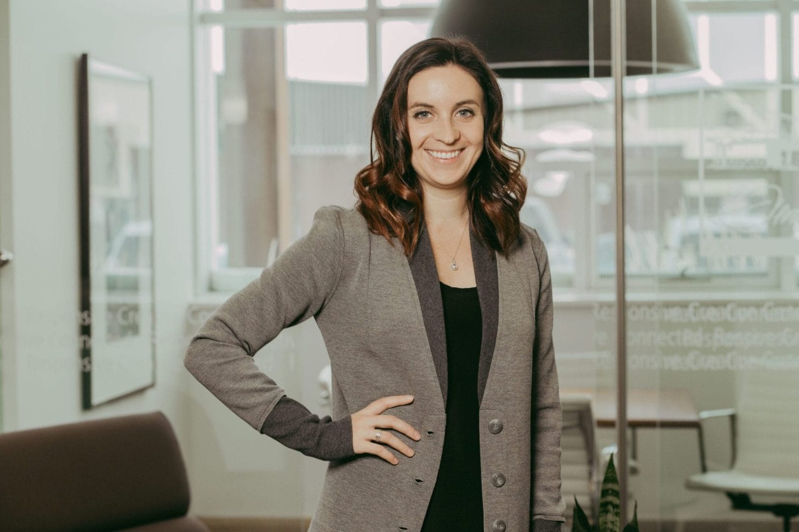 A woman in a gray blazer standing in an office.