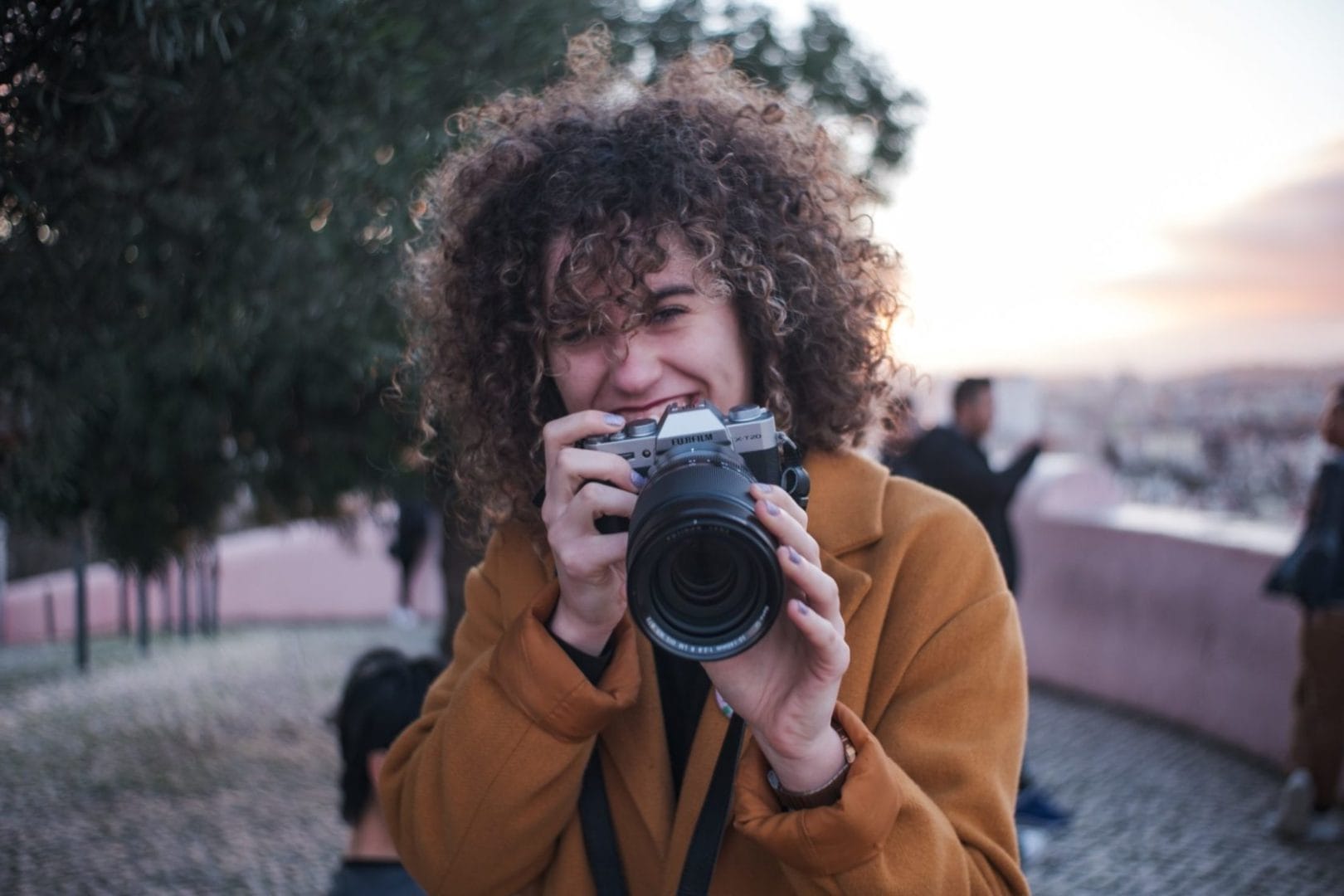 A woman with curly hair taking a picture with her camera.