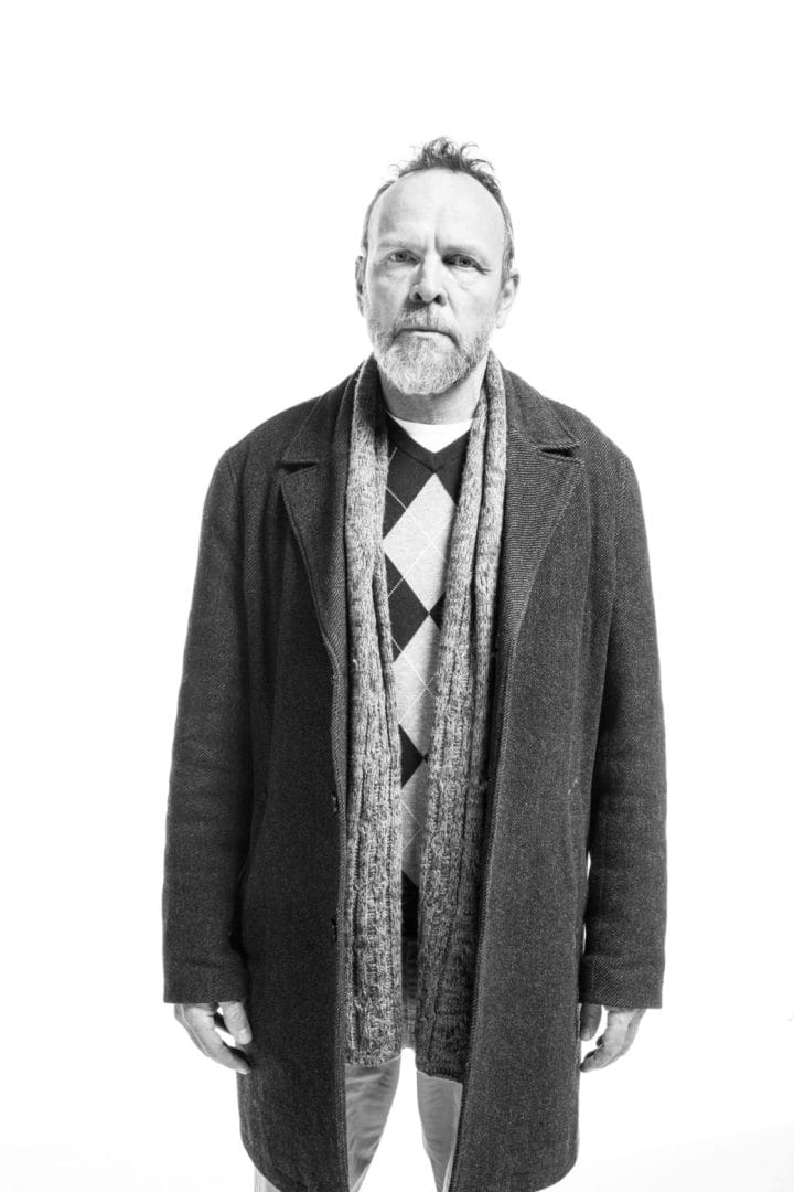 A black and white photo of a man in a coat and scarf.