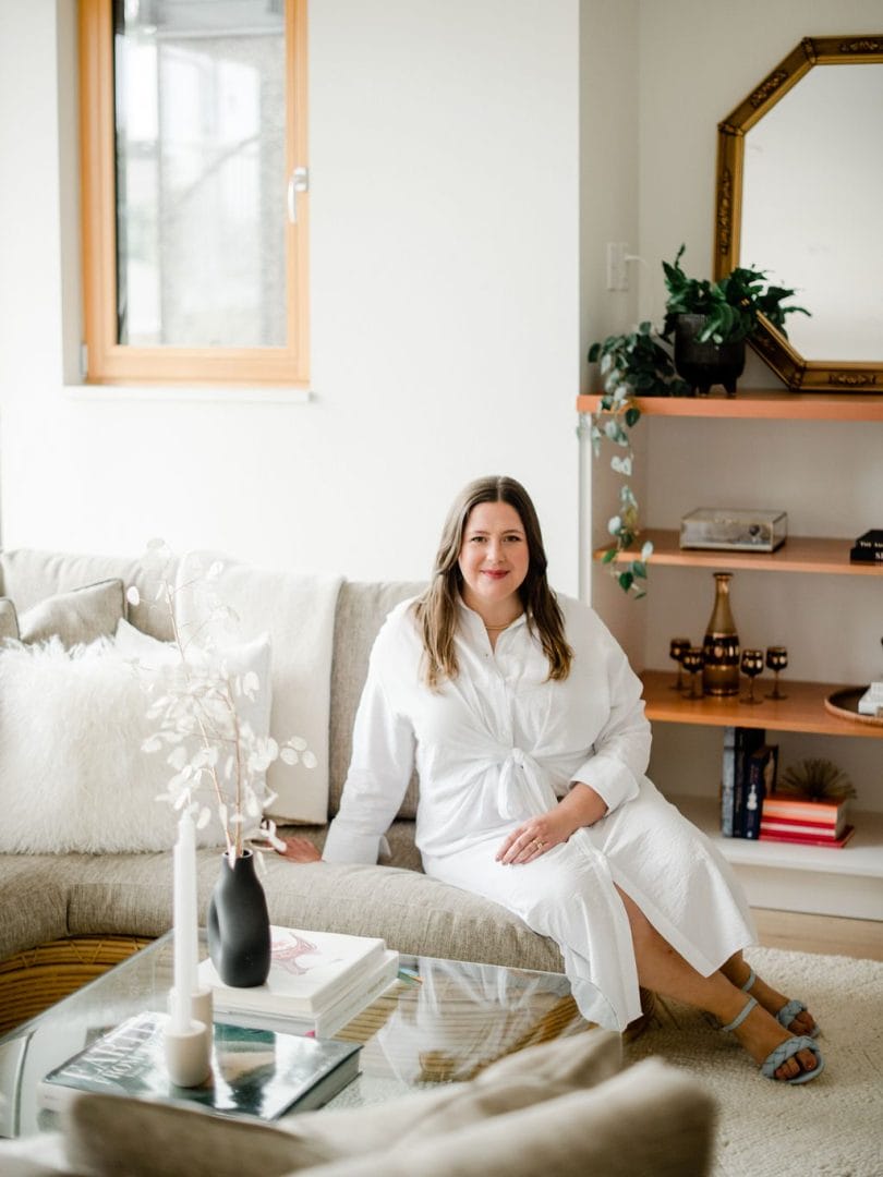 A woman in a white robe sitting on a couch in a living room.