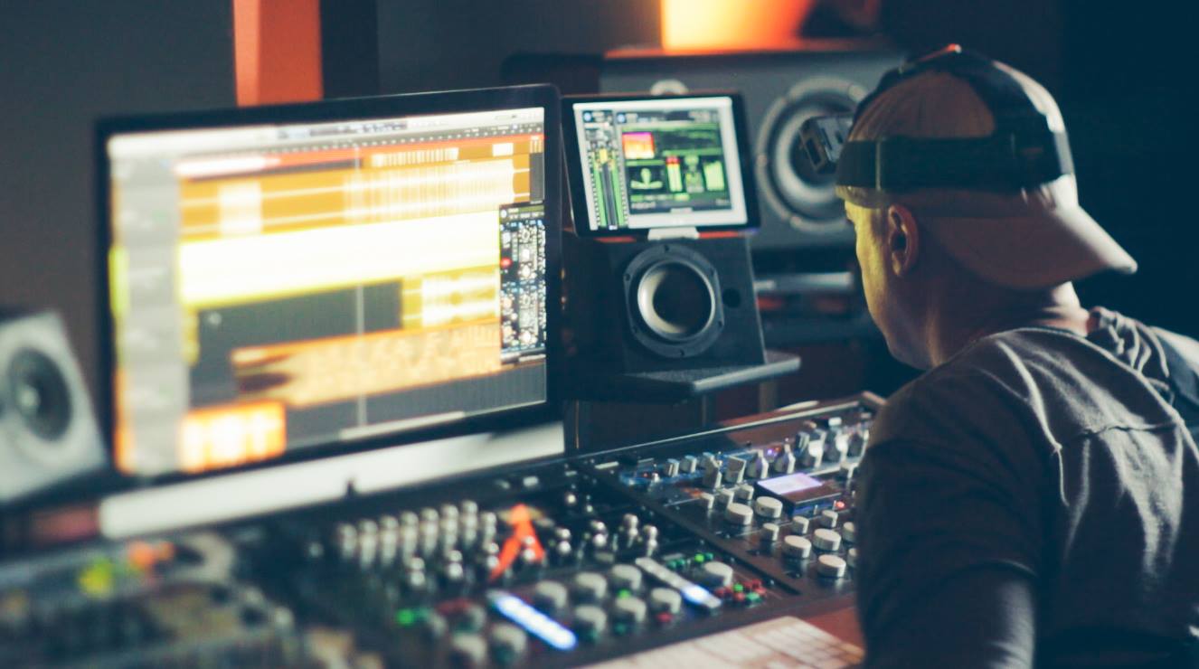 A man in a hat is working in a recording studio.