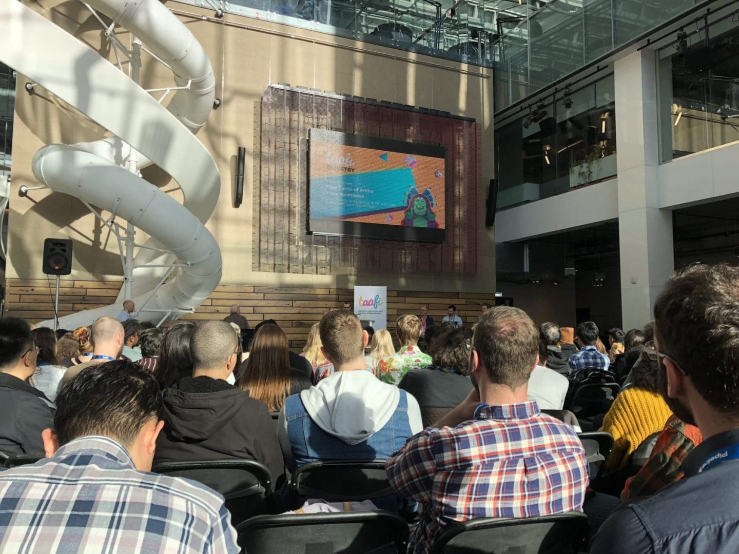 A crowd of people watching a presentation in an auditorium.