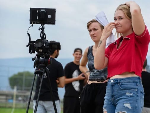 A group of Centre for Art and Design students are standing in front of a camera outdoors in summer.