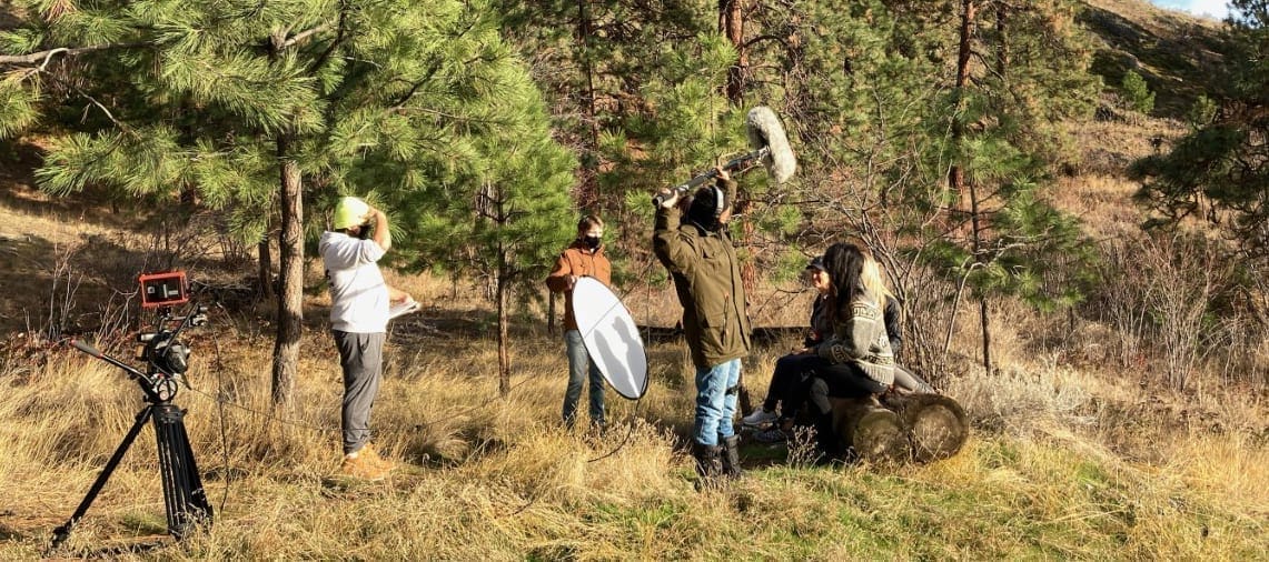 A group of people standing in a field with a camera.