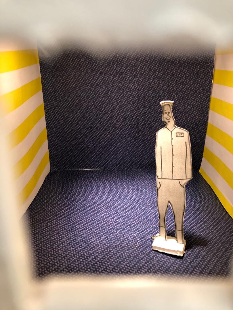 A paper model of a man standing in a box.