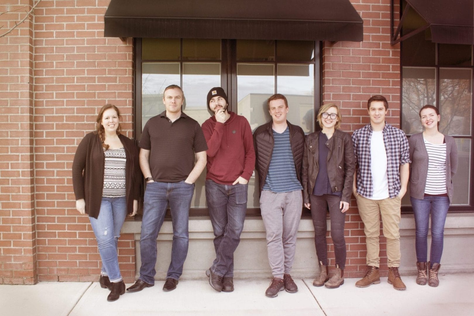 A group of people standing in front of a brick building.