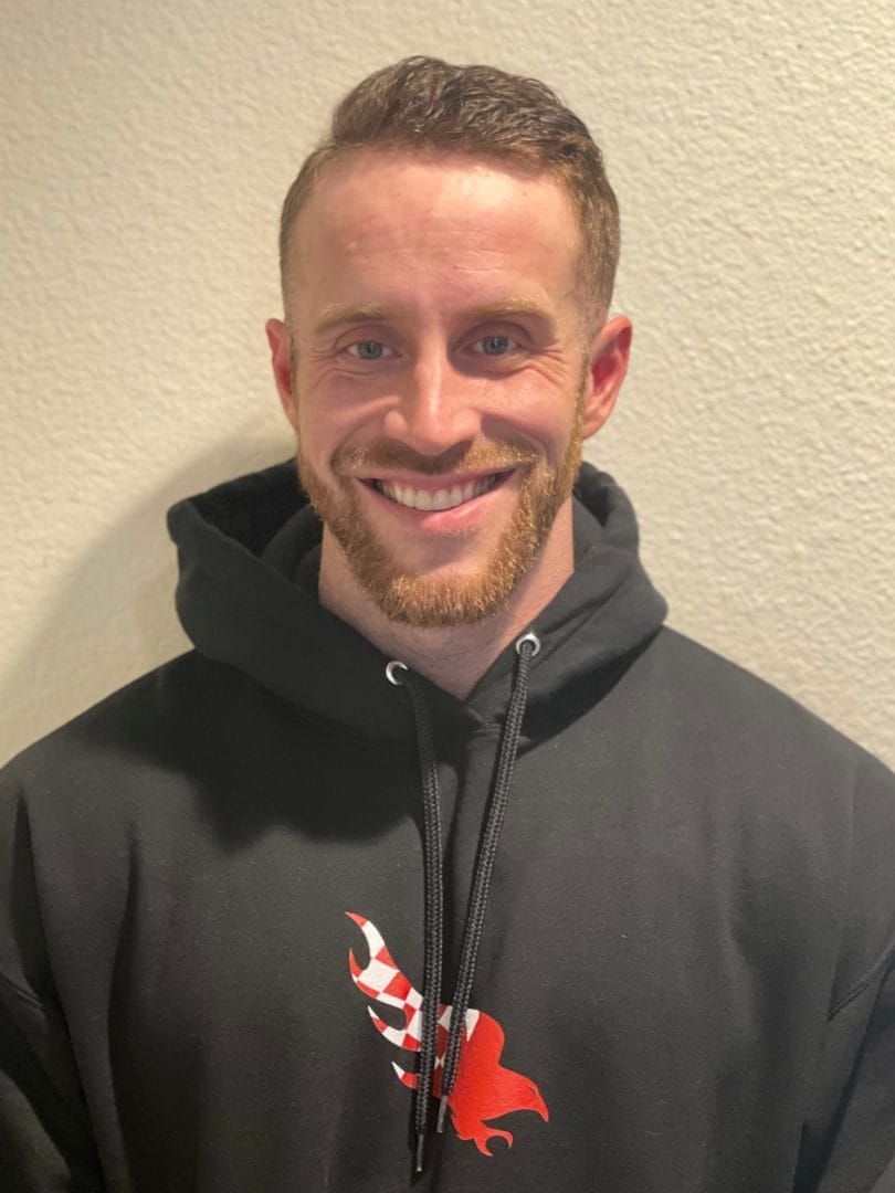 A man wearing a black hoodie with a red eagle on it.